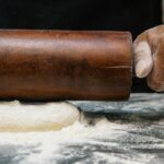 Close-up of a chef rolling dough with a wooden pin, capturing the art of baking.